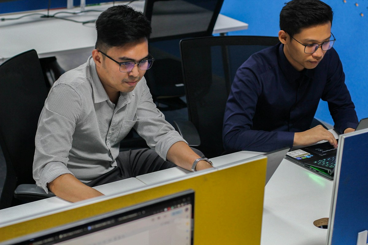 People working with desktop computers and a laptop in an office